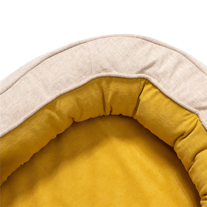 Beige oval dog bed with soft yellow interior lining for pet comfort.