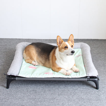 Corgi resting on elevated dog bed with soft green cushion and gray edges.